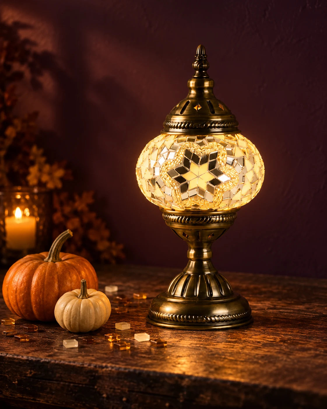 A glowing Turkish mosaic lamp styled with pumpkins for Halloween