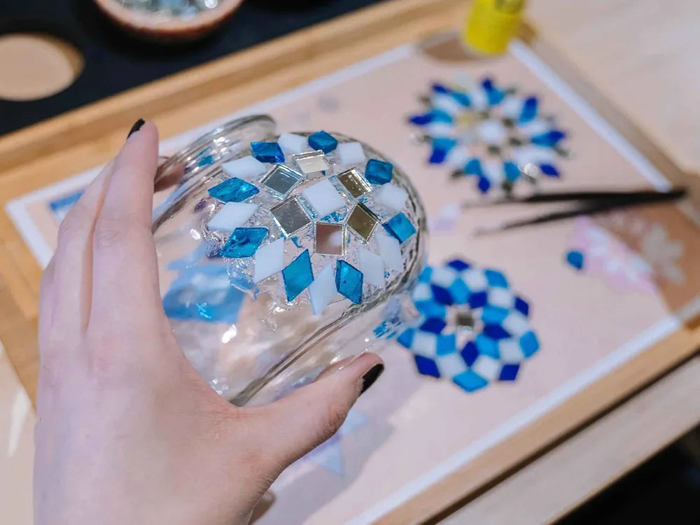 Hands arranging mosaic glass on a globe
