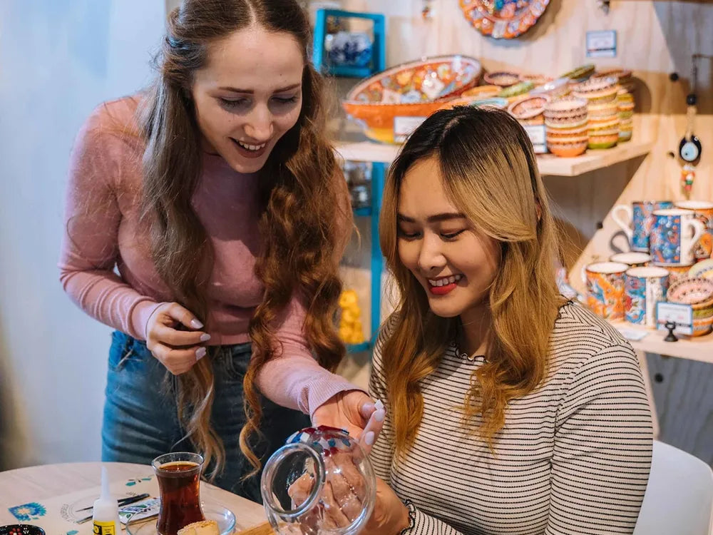 Instructor helping a guest make a mosaic lamp