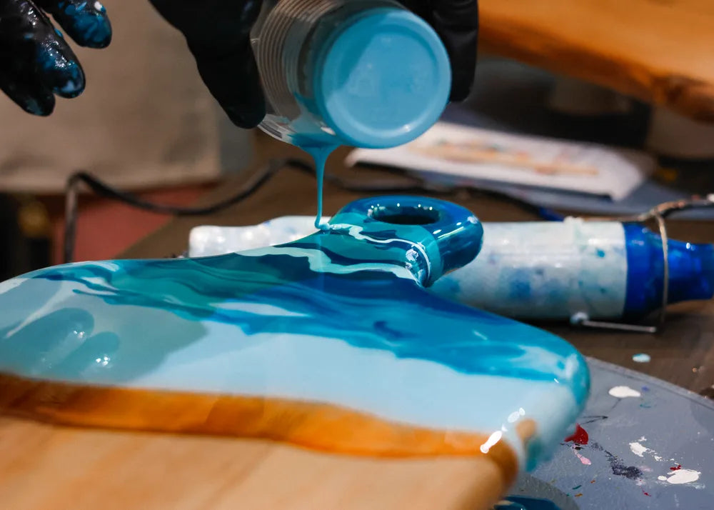 Blue resin being poured onto a wooden board